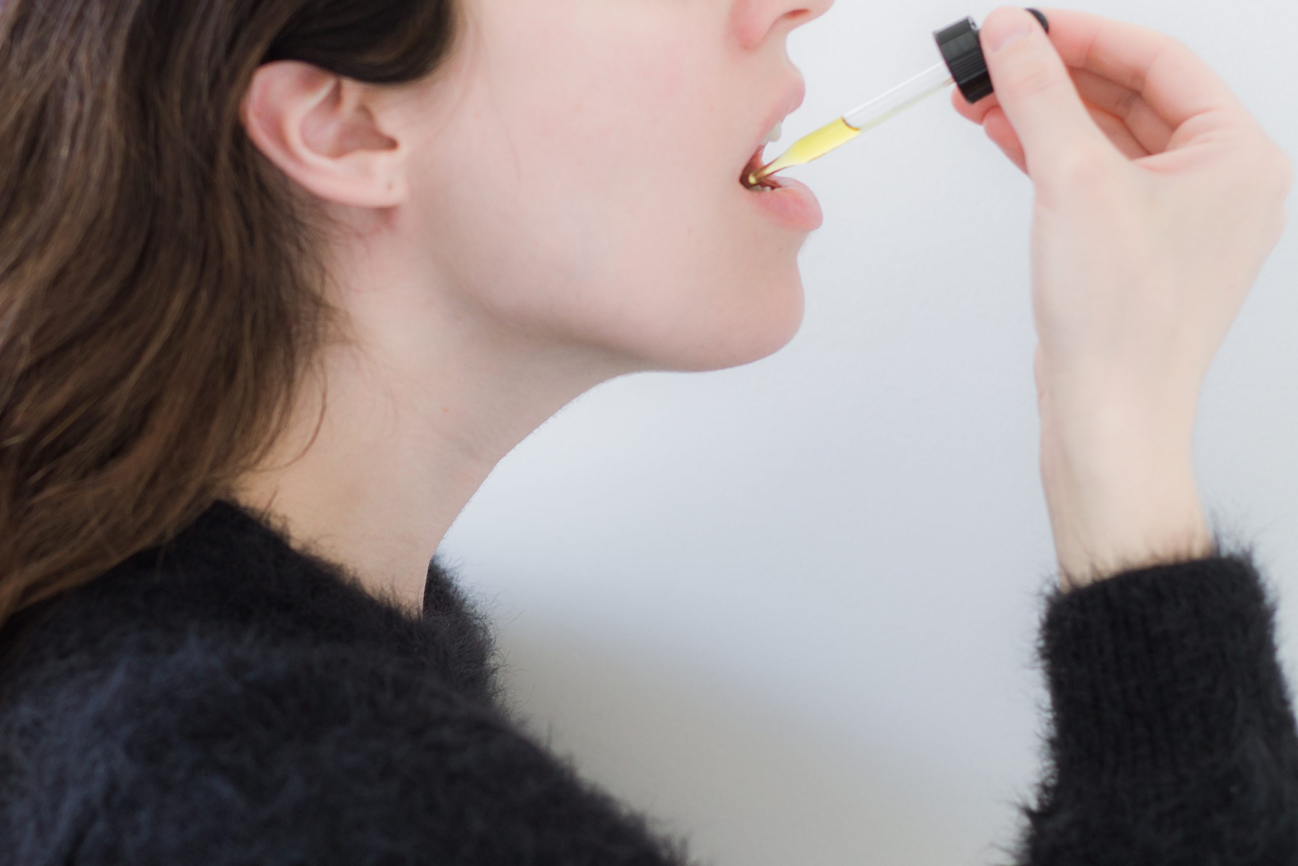 woman consuming cbd tincture under tongue